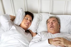 Woman trying to sleep is annoyed by her husband's snoring