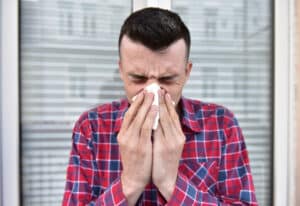 Woman with pollen allergy tries to improve her breathing. Man with recurrent sinus infection blows his nose into a tissue.
